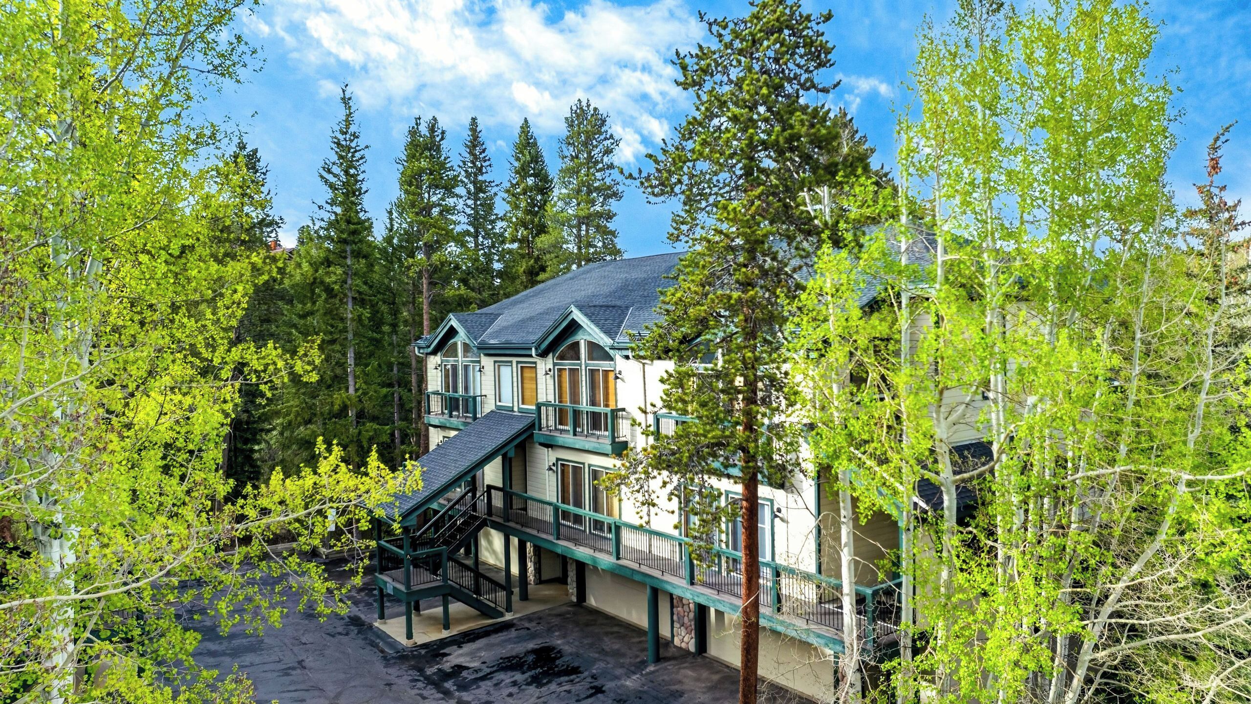 A two-story house with a balcony, surrounded by trees.