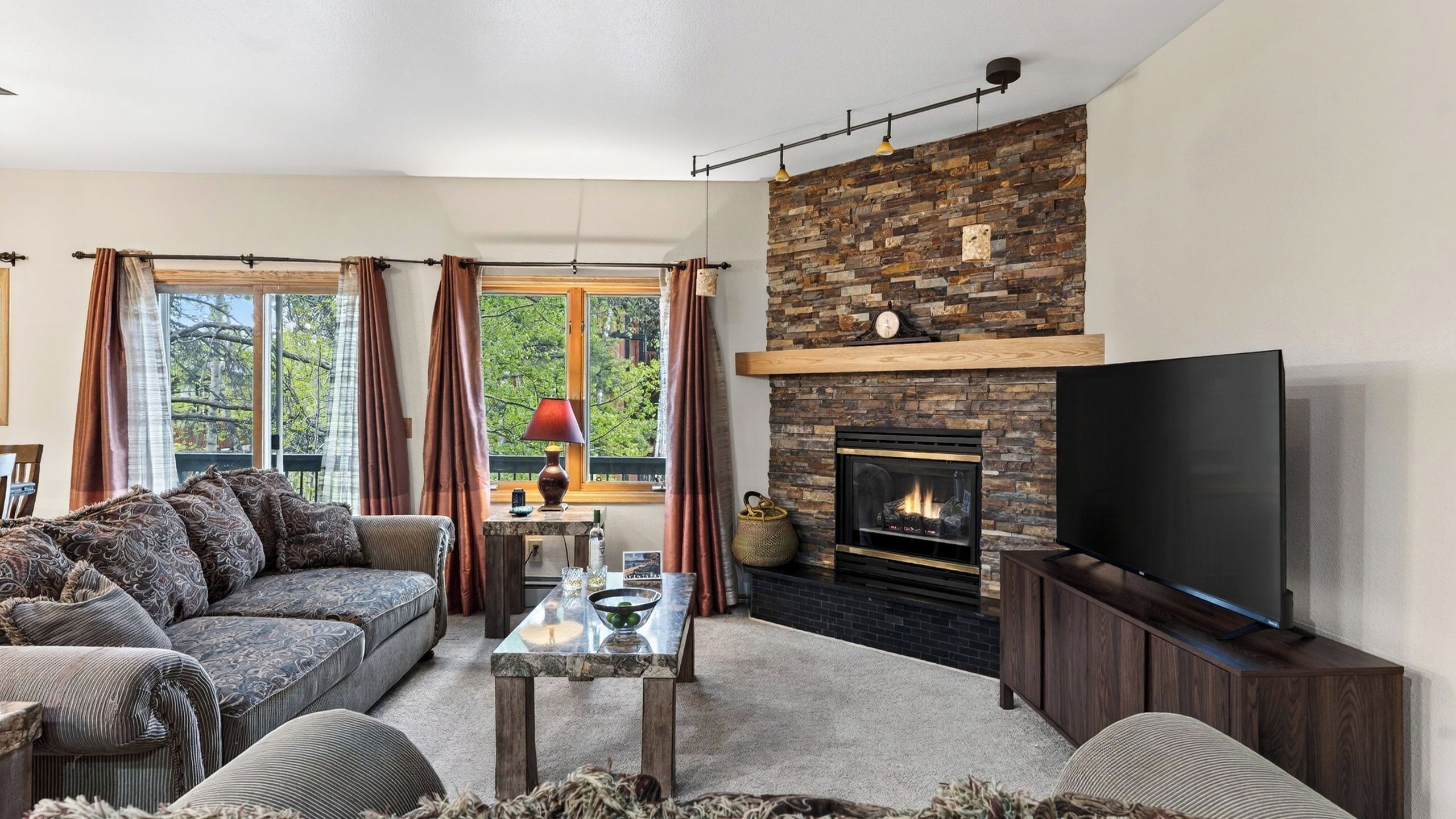A living room with a sofa, a coffee table, a fireplace, and a TV.