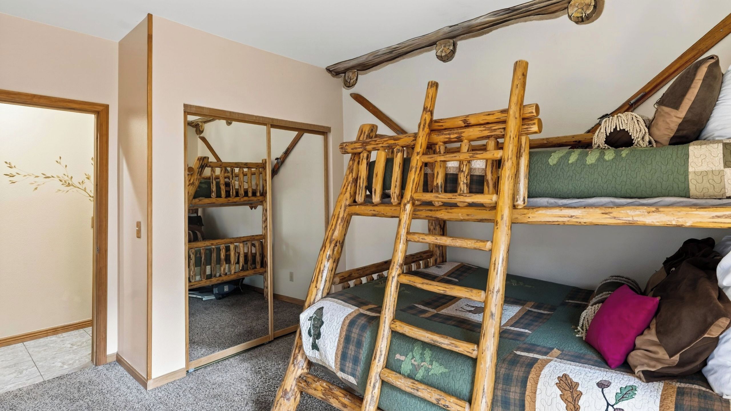 A bunk bed with a ladder, a wooden ladder, and a door with a decorative design.