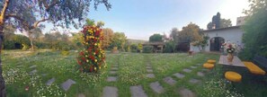 Un jardín con un arreglo floral central, piedras para caminar y mobiliario exterior.