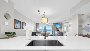 A modern kitchen with a central island, stainless steel sink, and a ceiling fan. - 🌴Island Princess 203 | Gulf Views | Pool + Hot Tub🌴 (Fort Walton Beach)