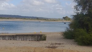 A sandy beach with a wooden fence, a body of water, and boats. - Apartment in Cap Ferret, across from Phare Beach (Lège-Cap-Ferret)