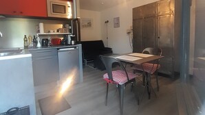 A compact kitchen with a microwave, refrigerator, and dining table with chairs. - Apartment in Cap Ferret, across from Phare Beach (Lège-Cap-Ferret)