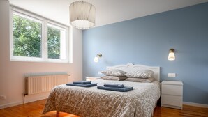 Een slaapkamer met een bed, nachtkastjes, een raam en een radiator.