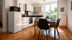Een moderne keuken met witte kasten, een zwart aanrecht en een eethoek met een tafel en stoelen.