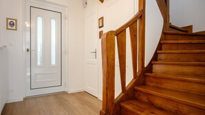 Een houten trap met een witte deur en een lichtschakelaar aan de muur.