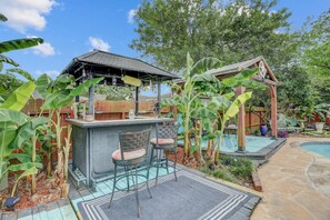 Un patio trasero con barra, piscina y estructura de madera.