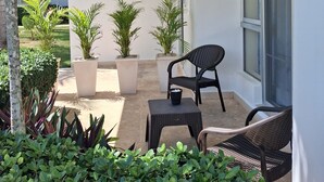 A covered outdoor area with potted plants, a small table, and two chairs. - Apartment with private access to the beach (Punta Cana)