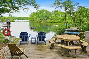 Eine Holzterrasse mit Adirondack-Stühlen, einem Picknicktisch und einem Rettungsring.