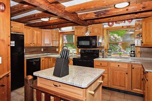 Eine Küche mit Holzausstattung, Granit Arbeitsplatten, einem schwarzen Kühlschrank, einer Mikrowelle und einem Herd.