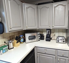 A kitchen with white cabinets, a toaster, a coffee maker, and a blender on the counter.