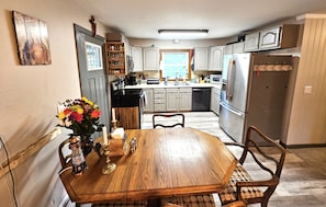 A kitchen with wooden cabinets, a dining table with chairs, and a vase with flowers.
