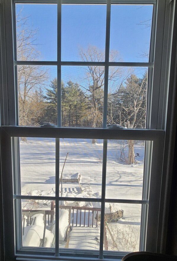 A window with a view of a snowy outdoor area, including a dock and dock chairs.