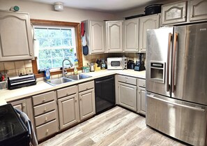 A kitchen with a stainless steel refrigerator, a built-in oven, a dishwasher, and wooden cabinets.