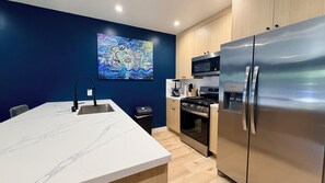 Una cocina moderna con encimera de mármol, electrodomésticos de acero inoxidable y una pared decorada en azul.