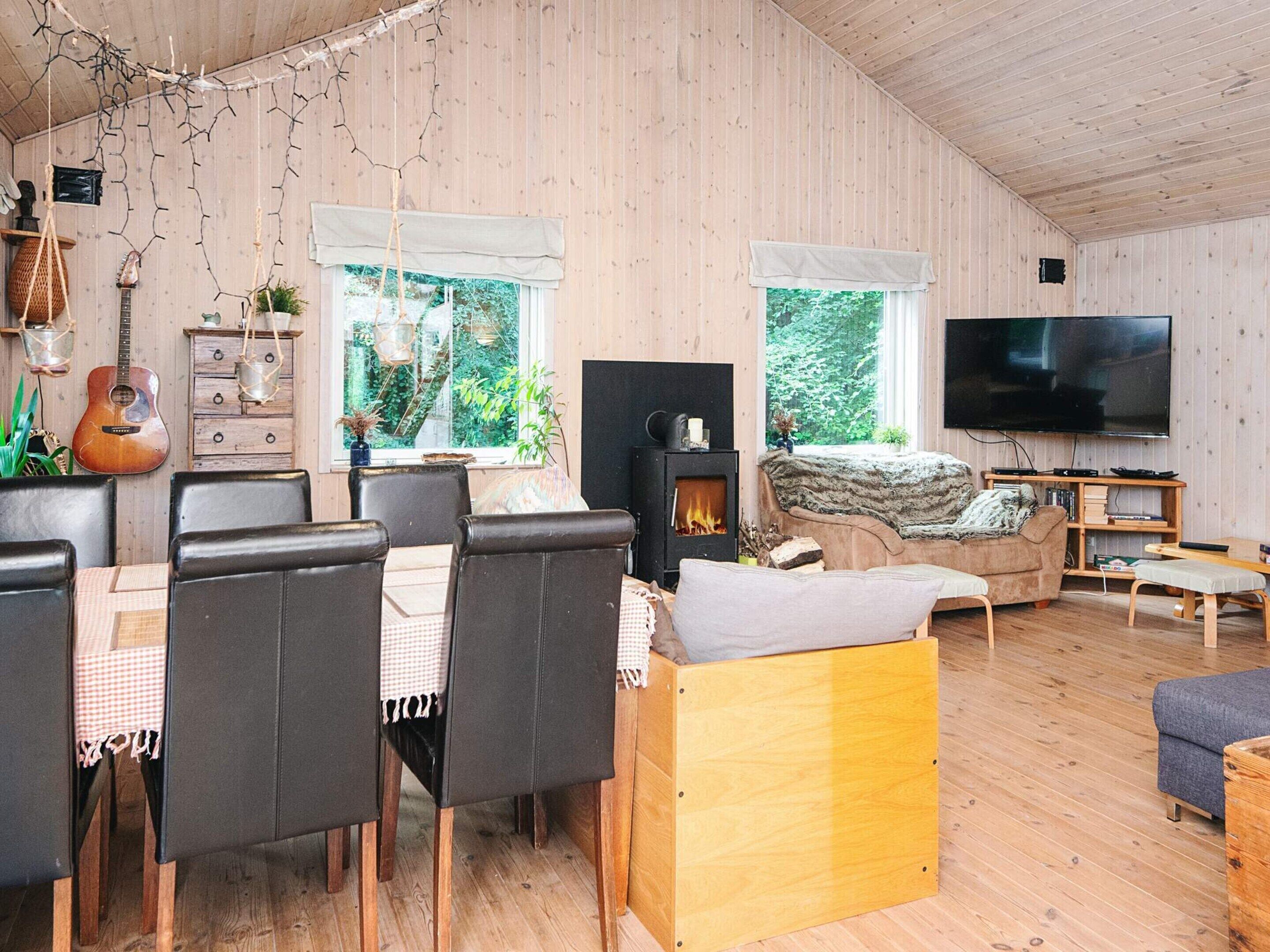 A cozy room with a dining table, chairs, a sofa, a TV, and a fireplace.