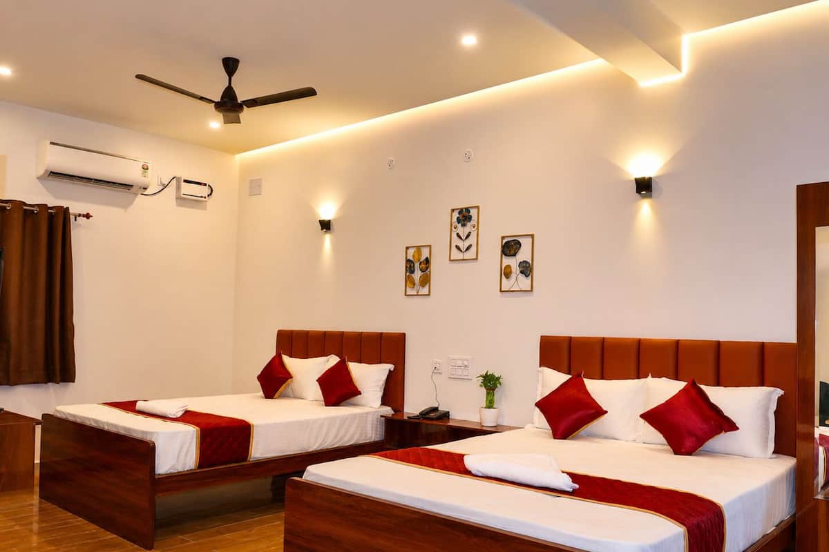 A hotel room with two wooden beds, a ceiling fan, an air conditioning unit, and wall-mounted light fixtures.