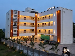 Un hotel de varios pisos con balcones, una zona de estacionamiento techada y un letrero que dice 'BAN'S PARADISE INN'.