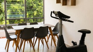 Een moderne eethoek met een tafel, stoelen en een hometrainer.