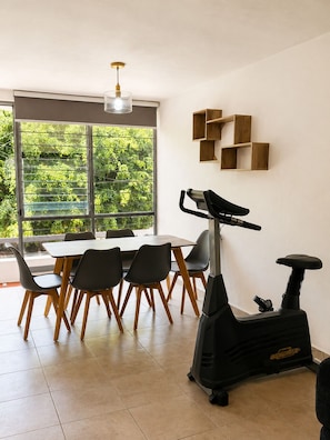 Un comedor moderno con una mesa, sillas y una bicicleta estática.