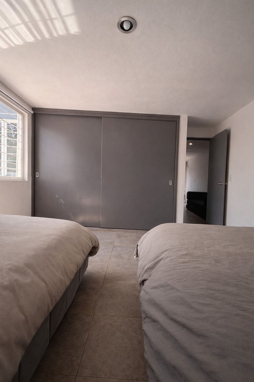 A bedroom with two beds, a closet, and a window.