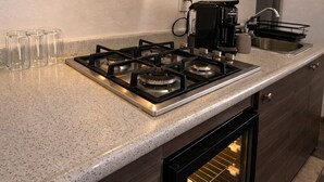 Een moderne keuken met een gasfornuis, een koffiezetapparaat en een inbouwoven.