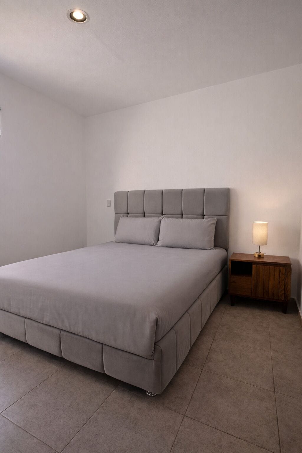 A bedroom with a bed, a nightstand, and a lamp.