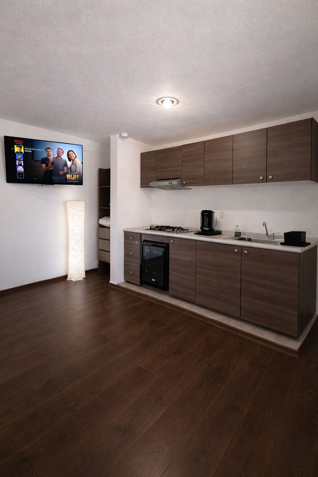 A modern kitchen with dark wooden cabinets, a built-in stove, and a black dishwasher.