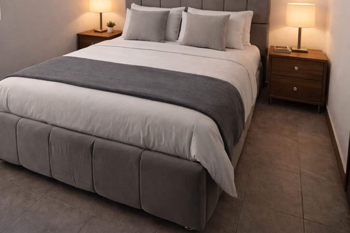 A neatly arranged bedroom with a large bed, two bedside tables, and a ceiling light.