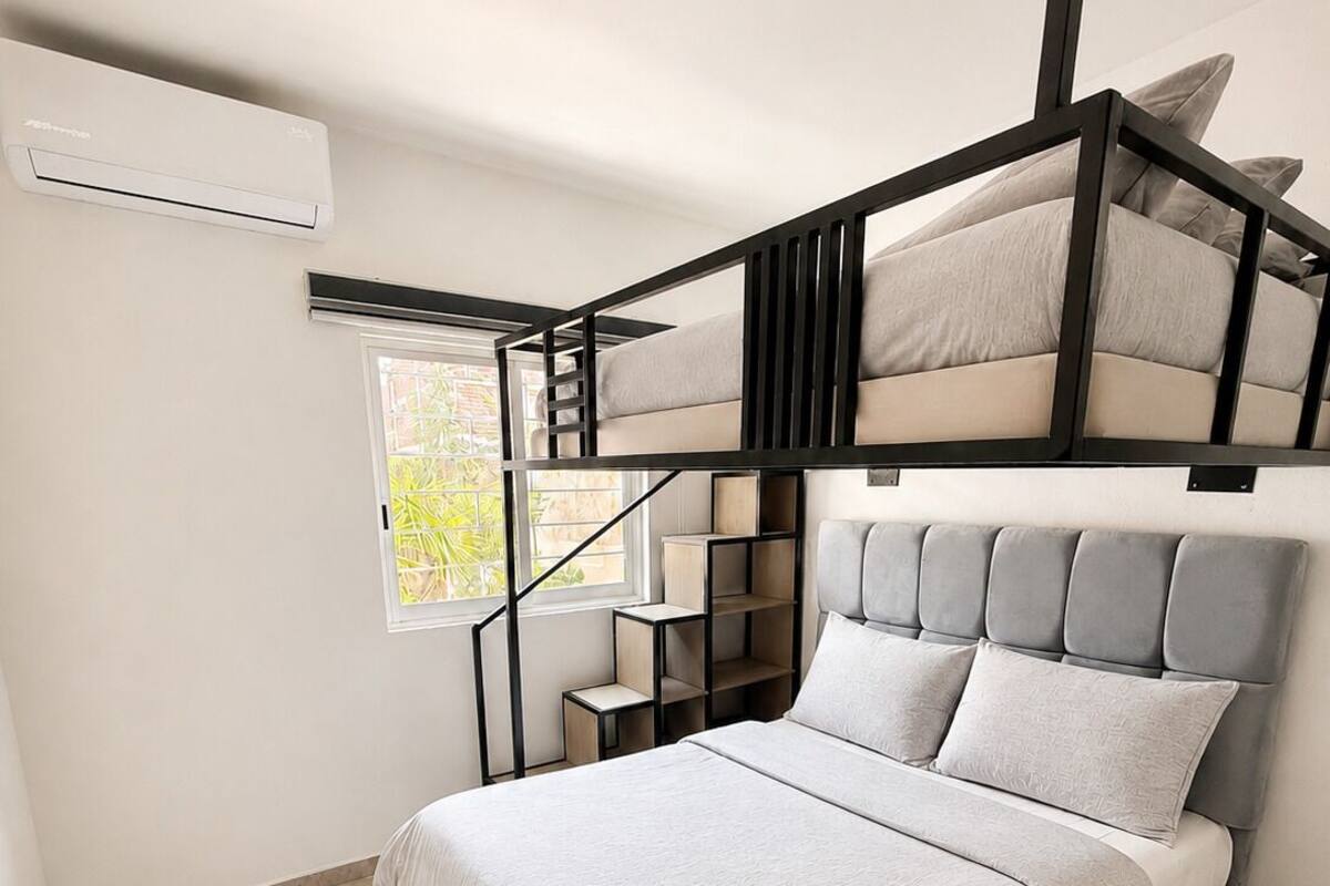 A modern bedroom with a bunk bed, a window, and a built-in shelf.