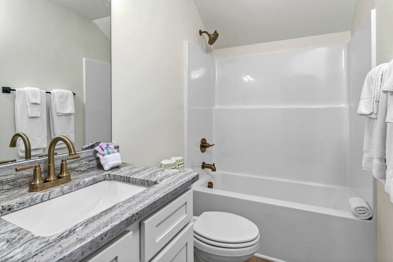 A bathroom with a marble sink, a bathtub, and a toilet.