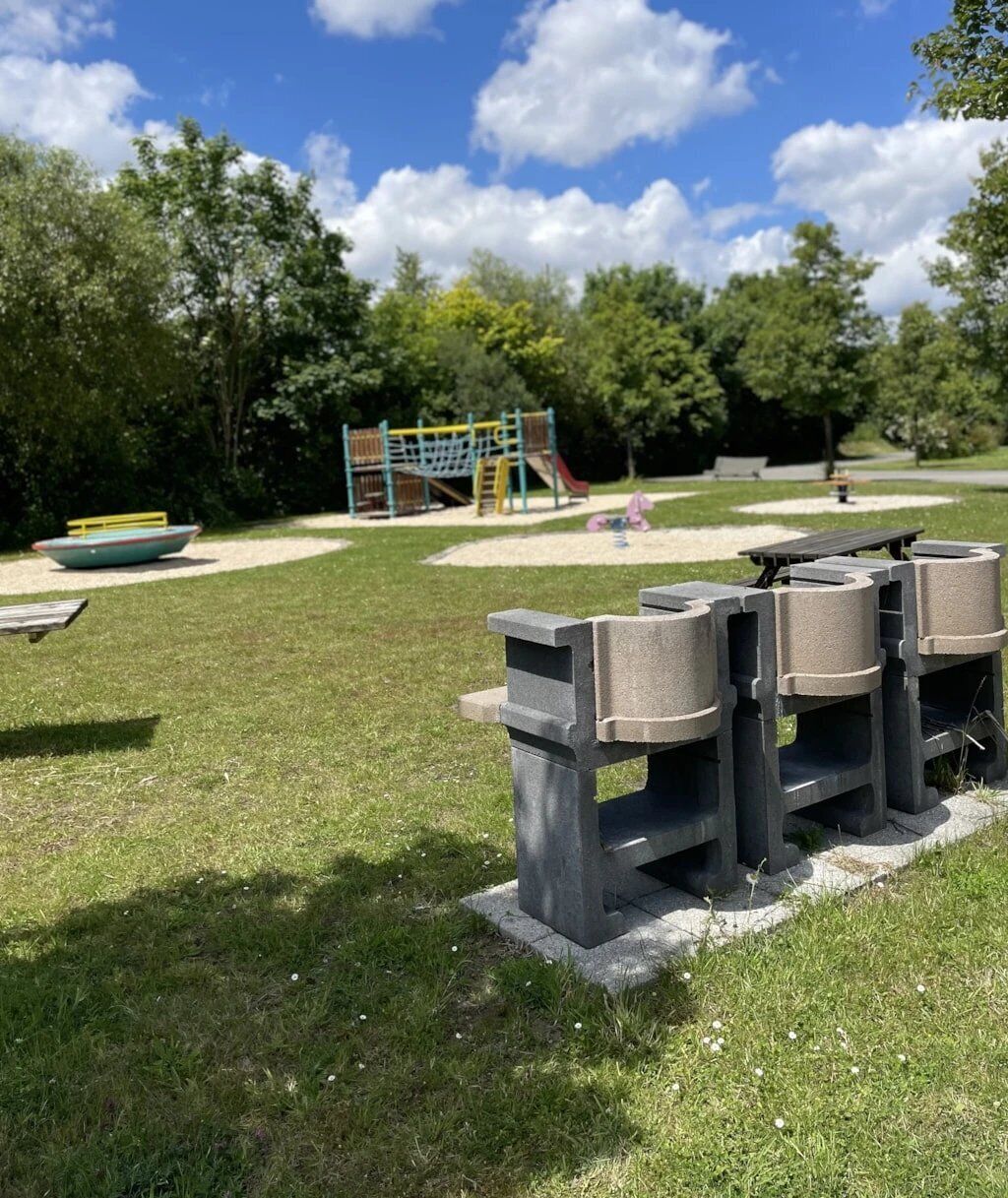 A park with a playground, a boat, and a seating area with benches.