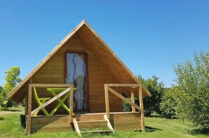 A wooden A-frame structure with a door and a small porch area. - Cabane 3 étoiles - Piscine  - ccbaica (Loudéac)