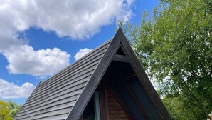 A small wooden cabin with a triangular roof, a porch, and a window.
