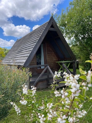 A small wooden cabin with a triangular roof, a porch, and a window.