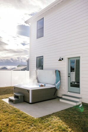 Une maison moderne dotée d’un jacuzzi, d’un patio couvert et offrant une vue sur les montagnes.