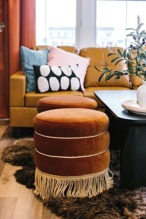 Un salon moderne avec un canapé, des poufs, une table basse et une plante.