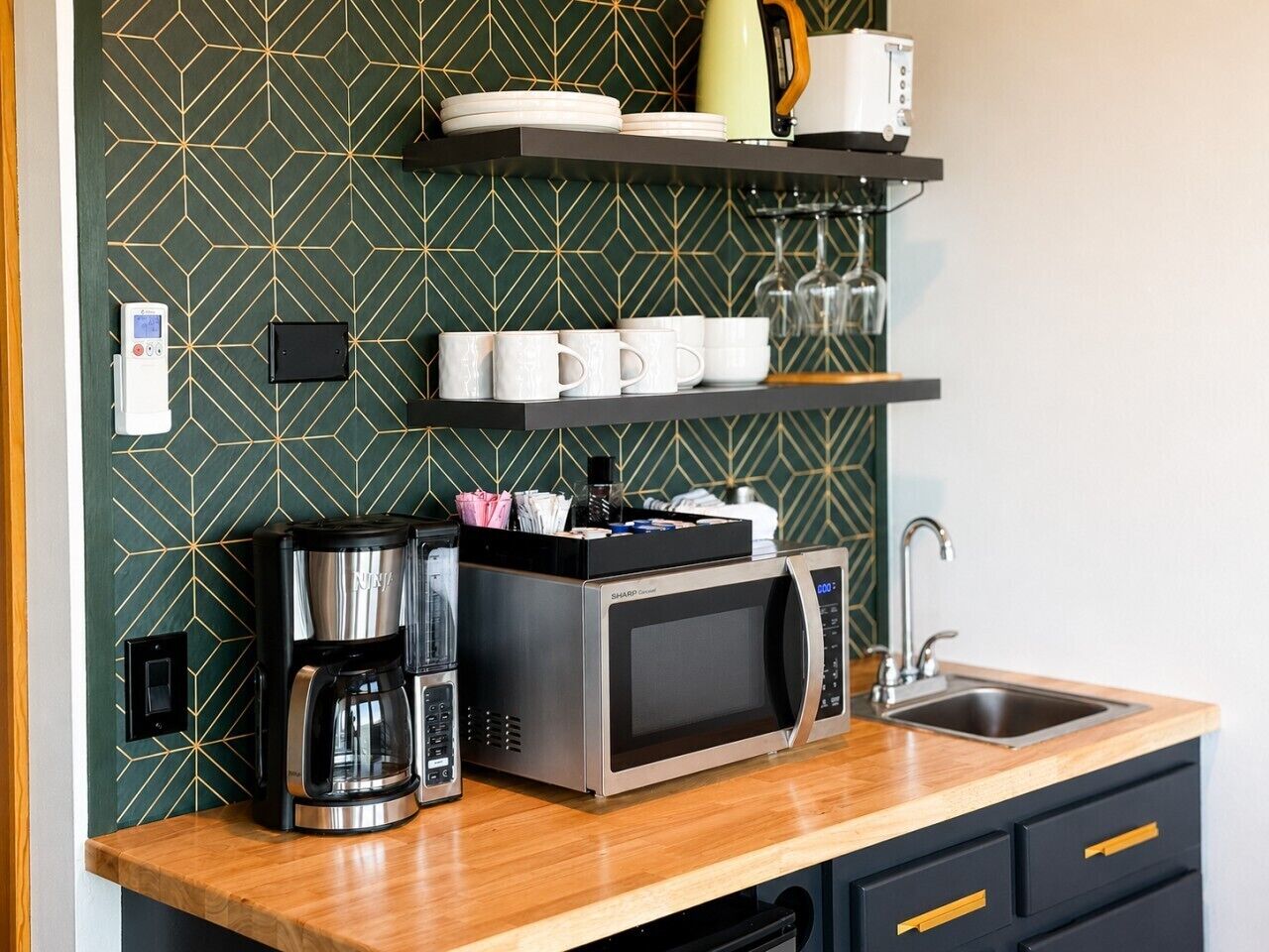 A compact kitchen with a microwave, coffee maker, and a sink.