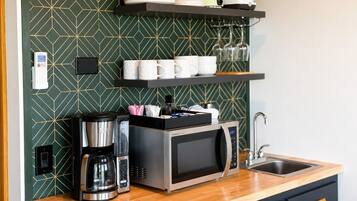 A compact kitchen with a microwave, coffee maker, and a sink.