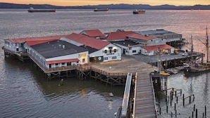 A waterfront property with multiple buildings, docks, and a pier extending into the water. - Pier 39 Over the water full River View + Fireplace (Astoria)