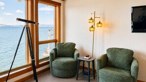 A room with a telescope, two green armchairs, a small table with a book, and a floor lamp. - Pier 39 Over the water full River View + Fireplace (Astoria)