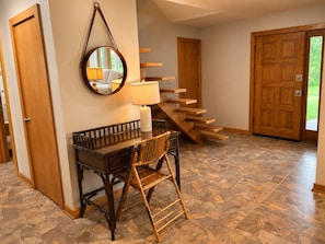 Ein Zimmer mit Schreibtisch, Stuhl, Spiegel, Lampe und einer Treppe.