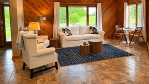 A living room with a sofa, armchair, coffee table, and dining area with chairs. - 3br farmhouse on horse farm - close to KY Horse Park, Hagyard + Rood & Riddle (Lexington)