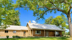 A two-story brick house with a metal roof, a large tree in front, and a well-maintained lawn. - 3br farmhouse on horse farm - close to KY Horse Park, Hagyard + Rood & Riddle (Lexington)