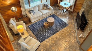 A cozy room with a stone floor, a sofa, a chair, a small table, and a fireplace. - 3br farmhouse on horse farm - close to KY Horse Park, Hagyard + Rood & Riddle (Lexington)