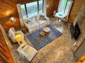 A cozy room with a stone floor, a sofa, a chair, a small table, and a fireplace.