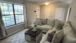 Una sala de estar con un sofá, una mesa de centro y una ventana con cortinas.