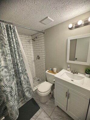 A bathroom with a shower, toilet, sink, and mirror. - 4-bedroom welcoming getaway in Jonesboro Ga (Jonesboro)