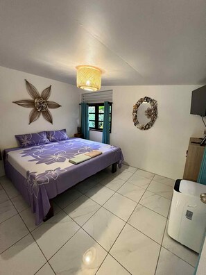 A bedroom with a bed, a wall-mounted flower decoration, a ceiling light, and a wall-mounted wreath.