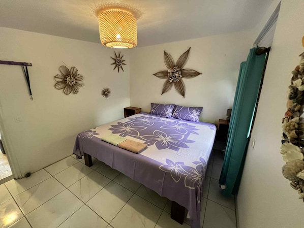 Une chambre à coucher comprenant un lit, des tables de chevet, un élément décoratif mural et un luminaire suspendu.